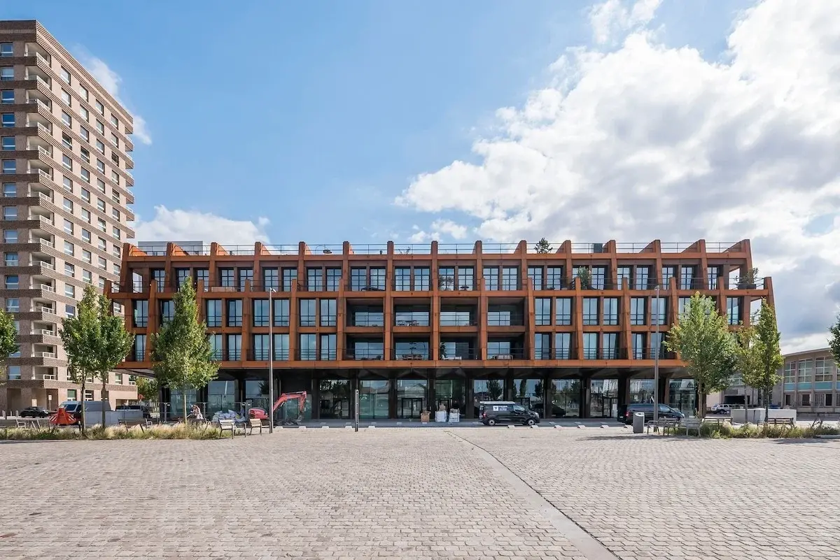 Modern appartementengebouw met roestkleurige stalen gevel aan een plein in Antwerpen