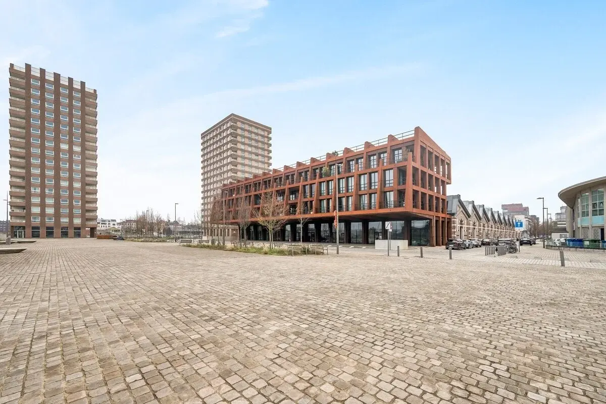 Modern appartementengebouw met roestkleurige stalen gevel aan een plein in Antwerpen