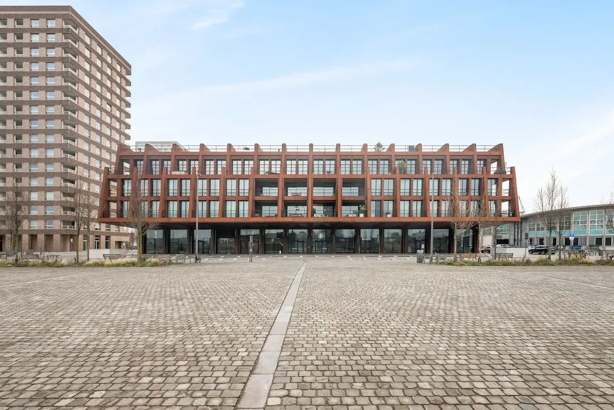 Modern appartementengebouw met roestkleurige stalen gevel aan een plein in Antwerpen